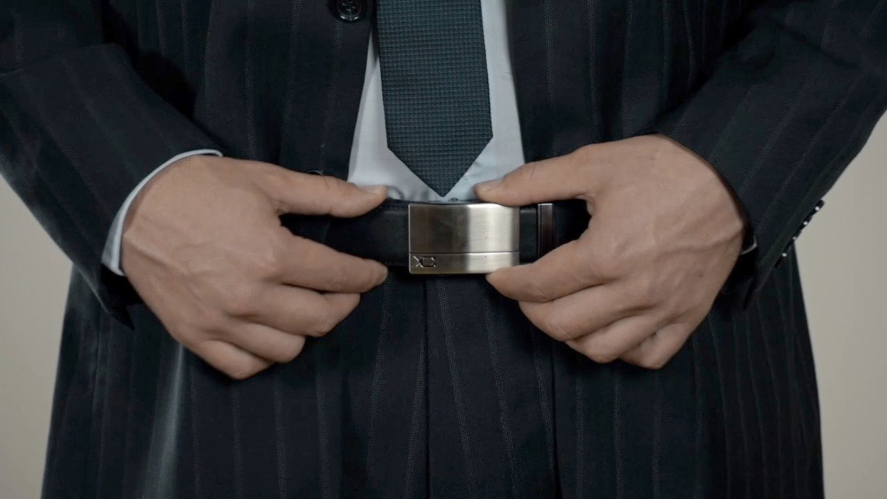 Schwarzer Ledergürtel für Männer im Anzug. Die silberne Gürtelschnalle aus Schweizer Design kommt dank Automatik-Verschluss ohne Löcher aus und kann stufenlos eingestellt werden.
