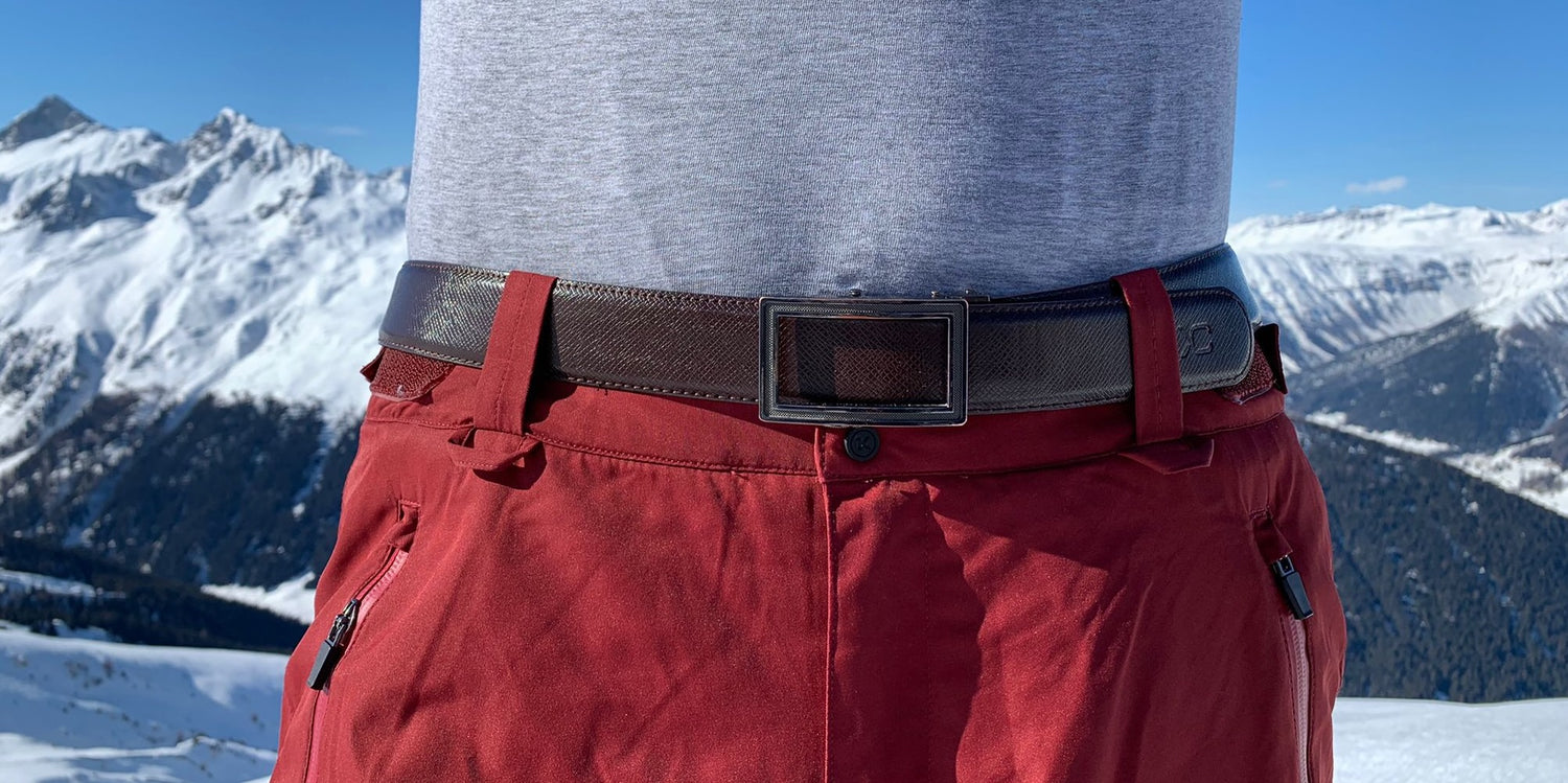 Brauner Ledergürtel für Männer mit Bergen im Hintergrund.  Die silberne Gürtelschnalle aus Schweizer Design  kommt dank Automatik-Verschluss ohne Löcher aus und kann stufenlos eingestellt werden.
